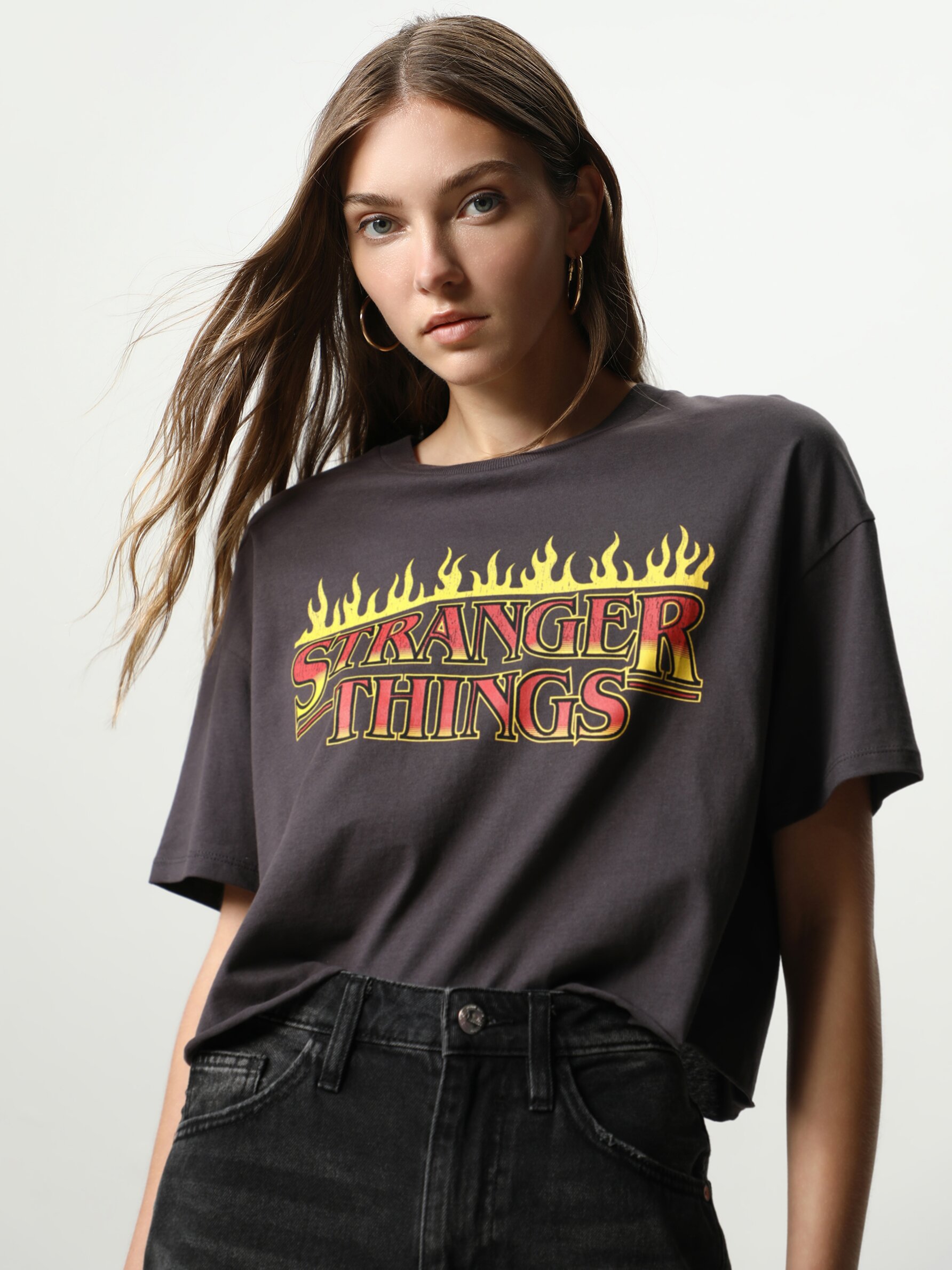 T-shirt imprimé Stranger Things™/© Netflix pour femme avec un col rond, des manches courtes et un bord-côte élastique au niveau du cou. Il a un imprimé sur le devant du vêtement.