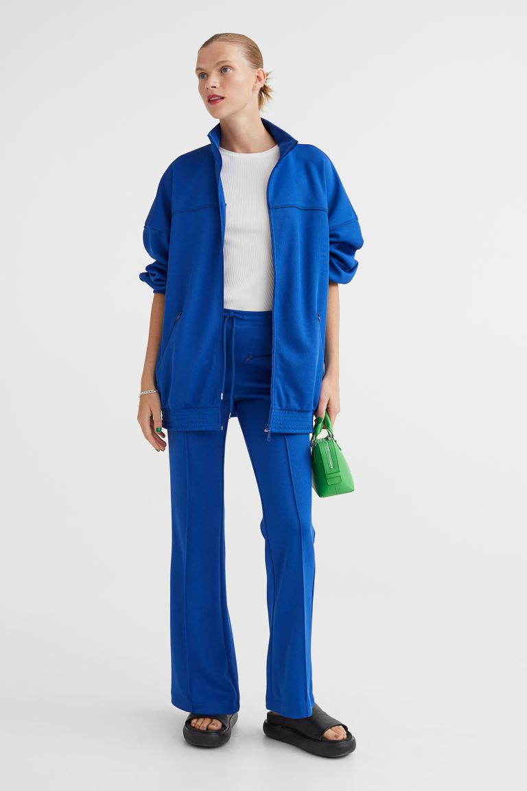 Pantalon coupe slim avec ourlets évasés. Cordon de serrage à la taille, poches zippées à l'avant et pinces à l'arrière. Plis de couture à l'avant et à l'arrière des jambes.