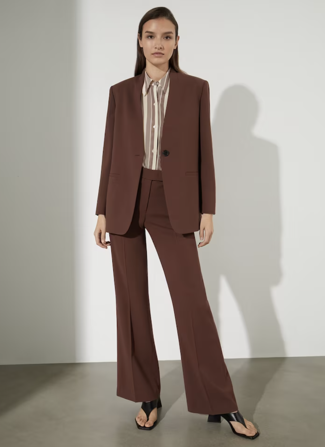 Blazer femme avec bouton et poches et pantalon évasé avec fermeture à l'avant.